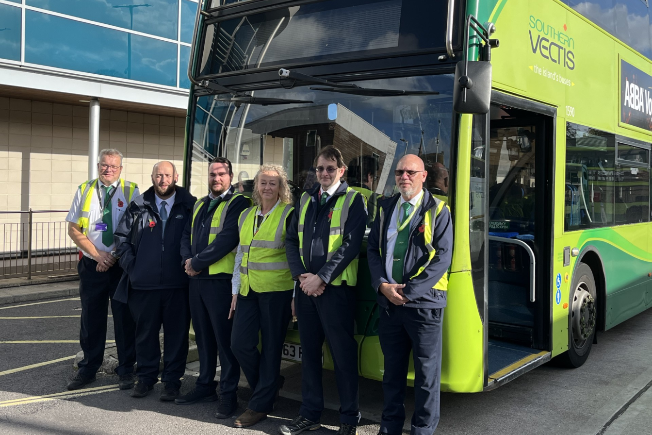bus drivers stood in front of bus wearing poppies
